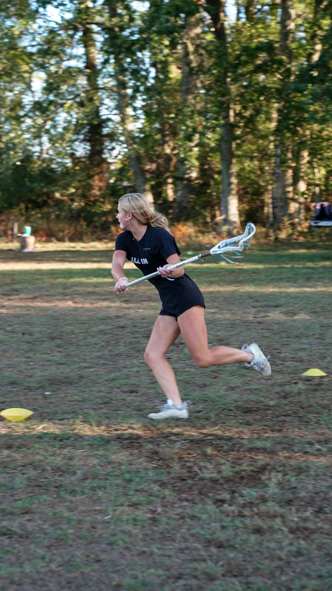 Player sprinting full speed with her stick cradled during a late afternoon practice